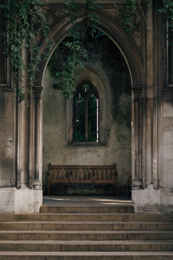 Serene view of an old Gothic archway with a wooden bench in a historic setting.